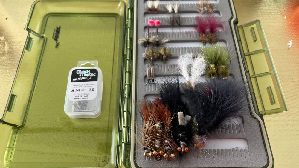 Flybox with various flies with a packet of A14 hooks on the left